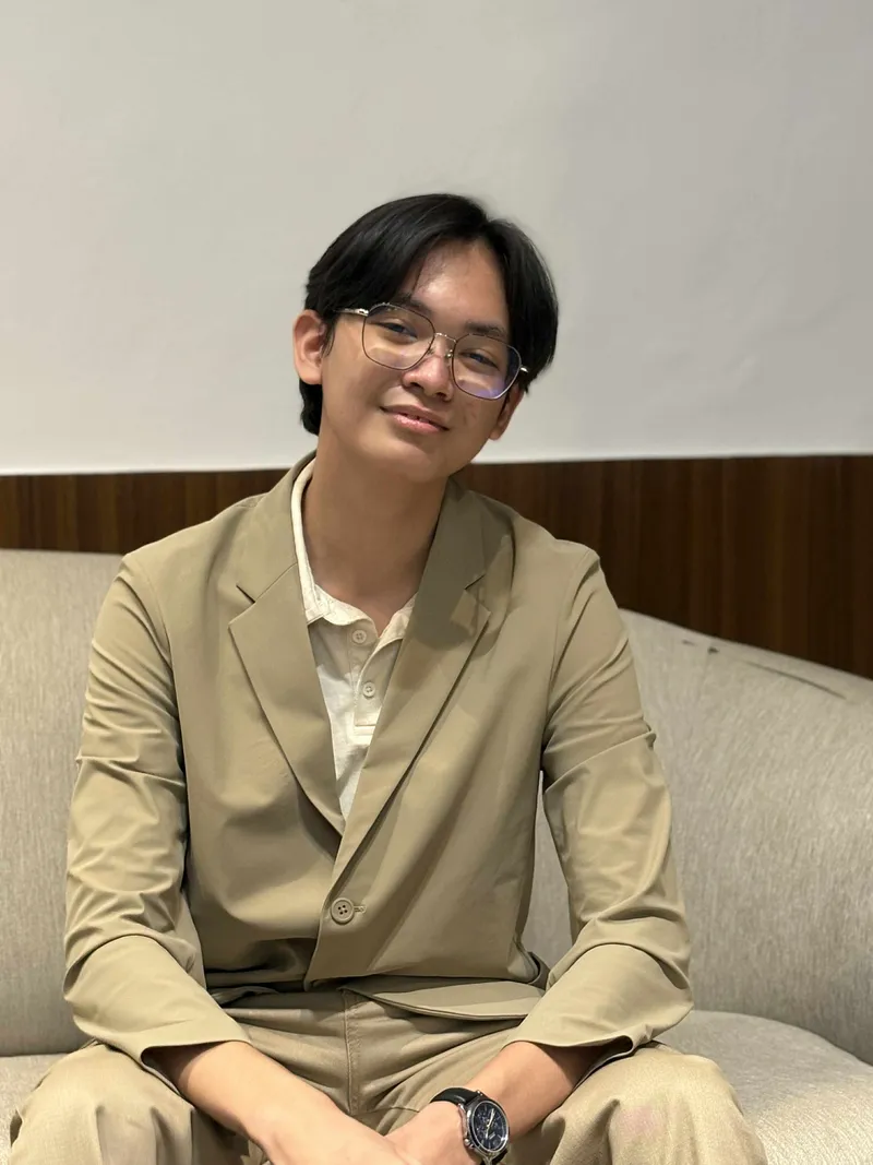 Sean in a beige suit, seated and smiling, at the Zero to One Hackathon in ASES Manila